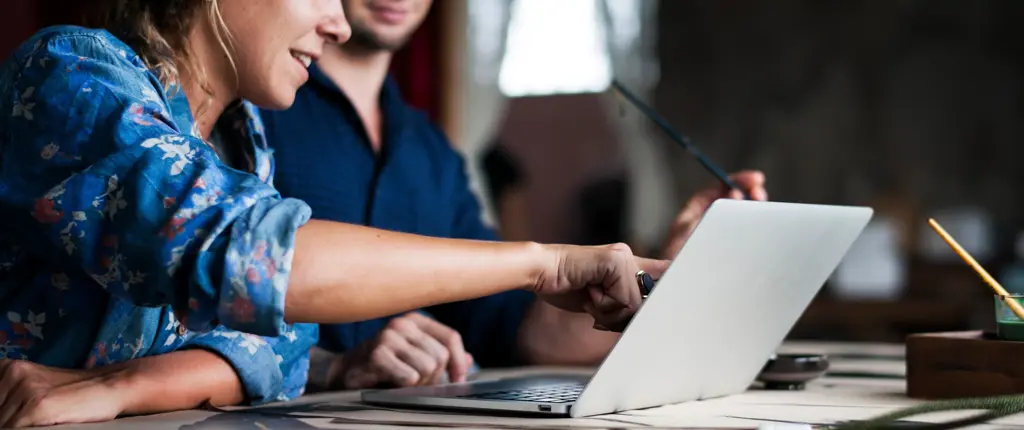 werknemer verwelkomt nieuwe collega met uitleg aan laptop